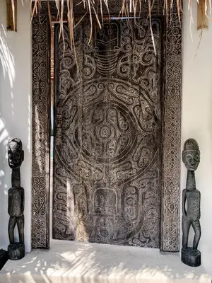 a large metal door in a room with two statues at Villa Obao in Seminyak