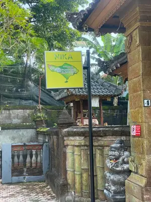 a sign in front of a building with a fish at Guest House Pondok Puspa Ayu in Kuta
