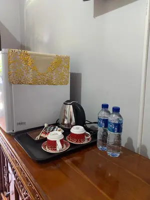 a microwave and two bottles of water on a wooden counter at Guest House Pondok Puspa Ayu in Kuta