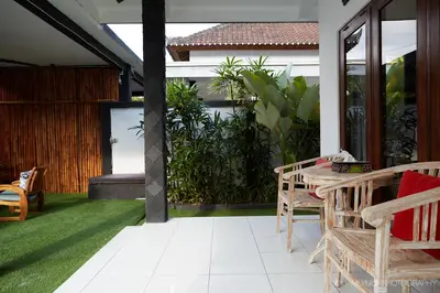 a patio with chairs and a table on a lawn at Villa Ari in Seminyak