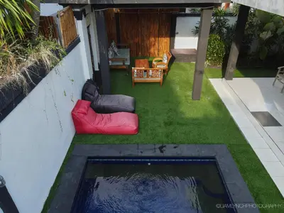 a small yard with a red couch on the grass at Villa Kaya in Seminyak