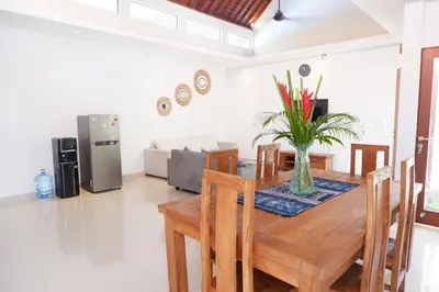 a dining room with a table with a vase of flowers on it at Villa Bristol in Seminyak