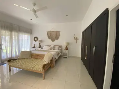 a bedroom with a bed and a couch and a fan at Villa Dharsan in Seminyak