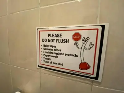 a sign on a bathroom wall with a do not flush sign at Villa Dharsan in Seminyak