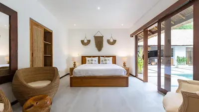 a bedroom with a bed and a chair in a room at Large 6-Bedroom Private Villa with Pool for Groups & Families - Umalas in Kerobokan