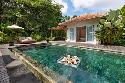 a pool with a tray of food in front of a villa at Villa Reina by SooBali - Spacious & Modern near Canggu with Butler-Cook, Private Pool and Tropical Gardens in Kerobokan