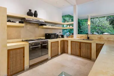 a kitchen with wooden cabinets and a stove top oven at Villa Reina by SooBali - Spacious & Modern near Canggu with Butler-Cook, Private Pool and Tropical Gardens in Kerobokan