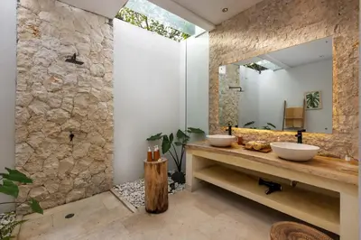 a bathroom with two sinks and a stone wall at Villa Reina by SooBali - Spacious & Modern near Canggu with Butler-Cook, Private Pool and Tropical Gardens in Kerobokan