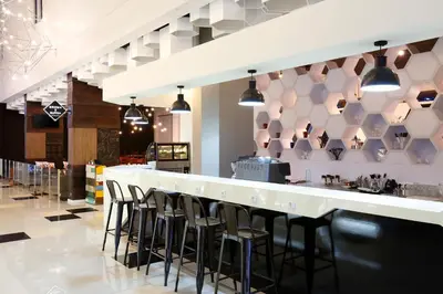 a bar in a restaurant with stools at Berry Biz Hotel Sunset Road in Seminyak