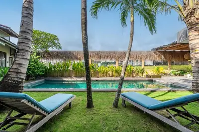 a villa with a swimming pool and palm trees at Villa Tarita Canggu in Kerobokan