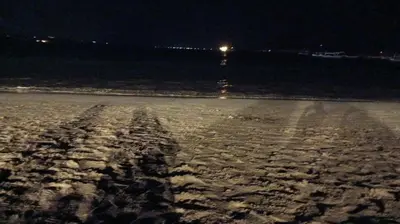 an empty beach at night with a light in the background at Lavanda guesthouse/homestay in Jimbaran