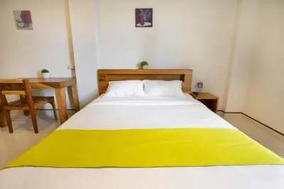 a bedroom with a bed with a yellow blanket on it at K Hostel Seminyak in Seminyak