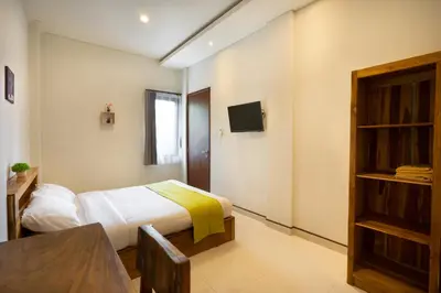 a bedroom with a bed and a table and a tv at K Hostel Seminyak in Seminyak