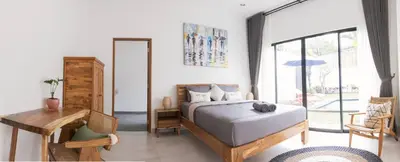 a bedroom with a bed and a desk and a window at VILLA NIKOLE in Seminyak
