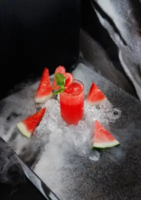 a glass of watermelon juice with watermelon slices on ice at The Mahata in Legian