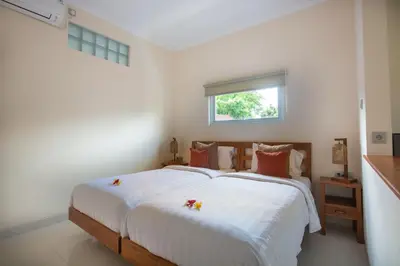 a bedroom with a bed with white sheets and a window at Donguri House Bali in Jimbaran