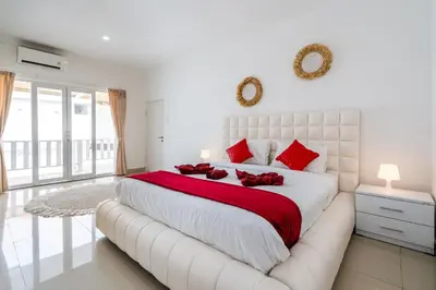 a white bedroom with a large bed with red pillows at Luxury minimalist villa White Angel in Seminyak, sleeps 21 people in total in Seminyak