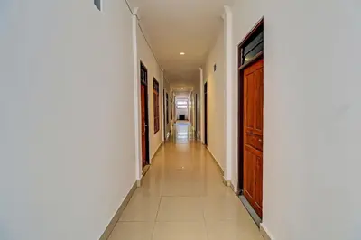 a long hallway with white walls and a wooden door at Capital O 92094 Hotel Kertha in Pesanggaran