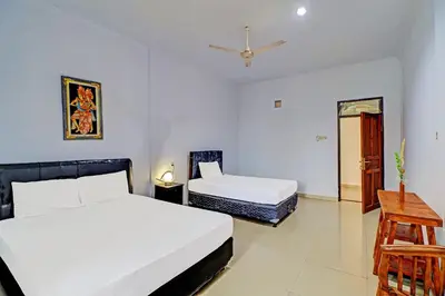 a bedroom with two beds and a table and a chair at Capital O 92094 Hotel Kertha in Pesanggaran
