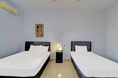 two beds in a room with white sheets at Capital O 92094 Hotel Kertha in Pesanggaran