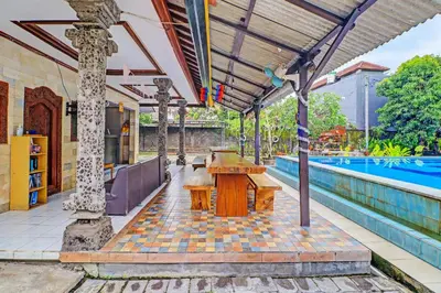 an outdoor patio with a table and a pool at Capital O 92094 Hotel Kertha in Pesanggaran