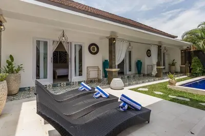 a villa with a swimming pool and blue chairs at Central & Charming 3bedr with private pool in Seminyak