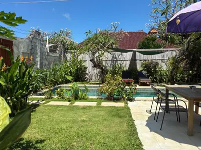 a backyard with a pool and a table and chairs at Villa Abhista Seminyak in Seminyak