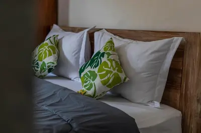 a bed with white and green pillows on it at Bali DD homestay seminyak in Seminyak
