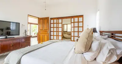 a bedroom with a large white bed and a flat screen tv at Taman Hijau Villa by iBali Management in Kerobokan