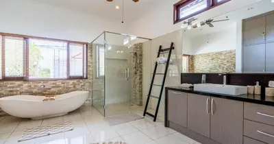 a bathroom with a tub and a glass shower at Taman Hijau Villa by iBali Management in Kerobokan