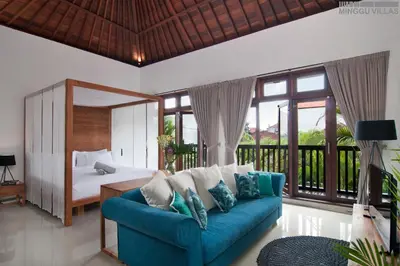 a living room with a blue couch and a bed at 8BR Villa Mason - Minggu Villas in Seminyak