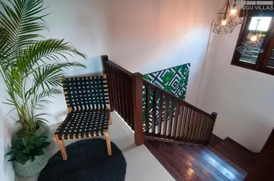 a wooden staircase with a chair and a plant at 8BR Villa Mason - Minggu Villas in Seminyak