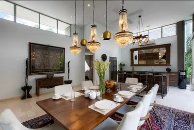 a dining room with a wooden table and white chairs at Villa Deh Simba at Seminyak Aramanis in Seminyak