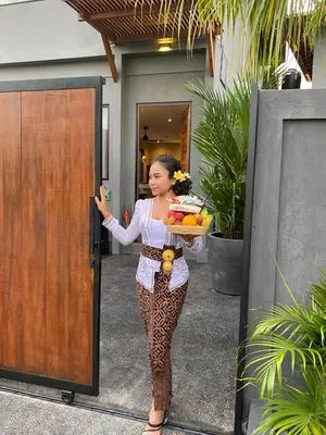 a woman holding a cake and a plate of fruit at ZenBali 1 Villa Canggu in Canggu