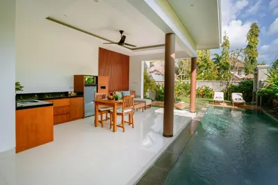 a kitchen and dining room with a table and a swimming pool at Kahayana Seminyak Villa in Seminyak