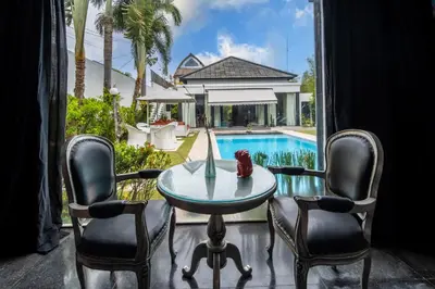 a dining room with a table and chairs and a pool at Villa Kalamansi Seminyak in Seminyak