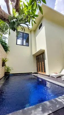 a villa with a swimming pool in front of a house at Abisha Villa Jimbaran in Jimbaran