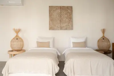 two beds in a room with white walls and two vases at Villa Folie by Alfred in Bali in Seminyak