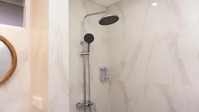 a shower with a shower head in a bathroom at Kedin's Inn in Denpasar