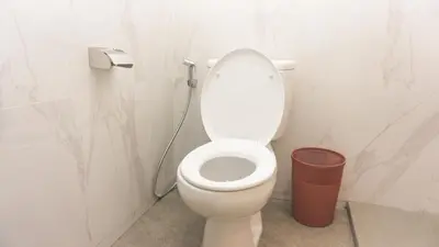 a bathroom with a toilet and a trash can at Kedin's Inn in Denpasar