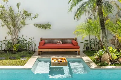 a red couch sitting next to a swimming pool at Premium 5 bd Luxury Central Villa 300m to beach & Ku De Ta in Seminyak