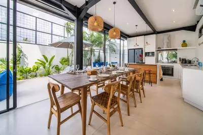 an open kitchen and dining room with a long wooden table and chairs at Villa Vantage Canggu in Canggu