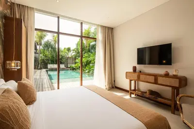 a bedroom with a bed and a tv and a window at Luxury 5bd Villa 5 Min From Berawa Beach in Canggu