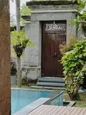 a house with a wooden door and a swimming pool at Villa Sriwedari - Seminyak in Seminyak