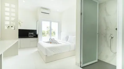 a white bedroom with a bed and a shower at The Axara Bali Managed by ARM Hospitality in Nusa Dua