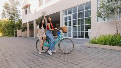 two women riding a bike in front of a building at The Axara Bali Managed by ARM Hospitality in Nusa Dua