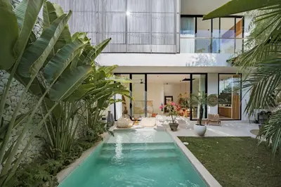 an indoor pool in a house with palm trees at Casa Noema in Kerobokan