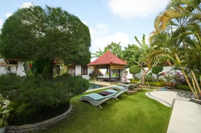 a garden with a swimming pool and a house at Villa Bulan Batubelig in Canggu