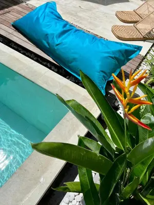 a blue pillow next to a plant next to a swimming pool at Rumah Ananda Bali - Balinese Villa Umalas in Canggu
