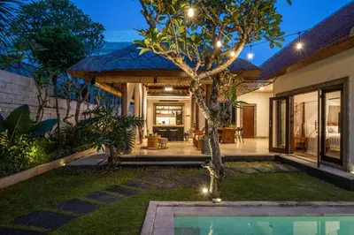a villa with a swimming pool at night at Rumah Ananda Bali - Balinese Villa Umalas in Canggu